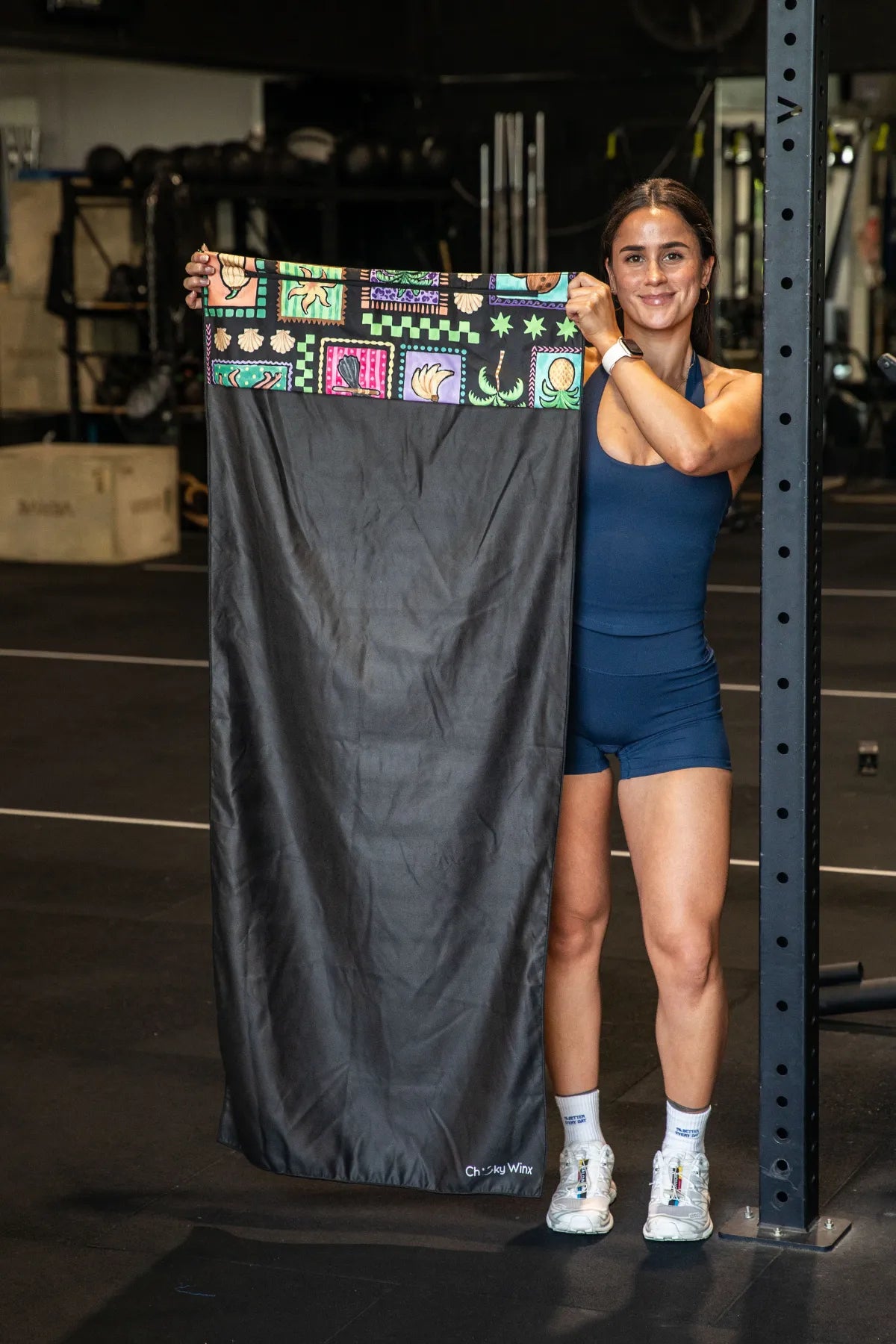 Black Tropics hooded gym towel by Nakari Studio, 140x60cm with zip pocket in hood, stays on gym bench, quick-dry and odour resistant by Cheeky Winx Australia.