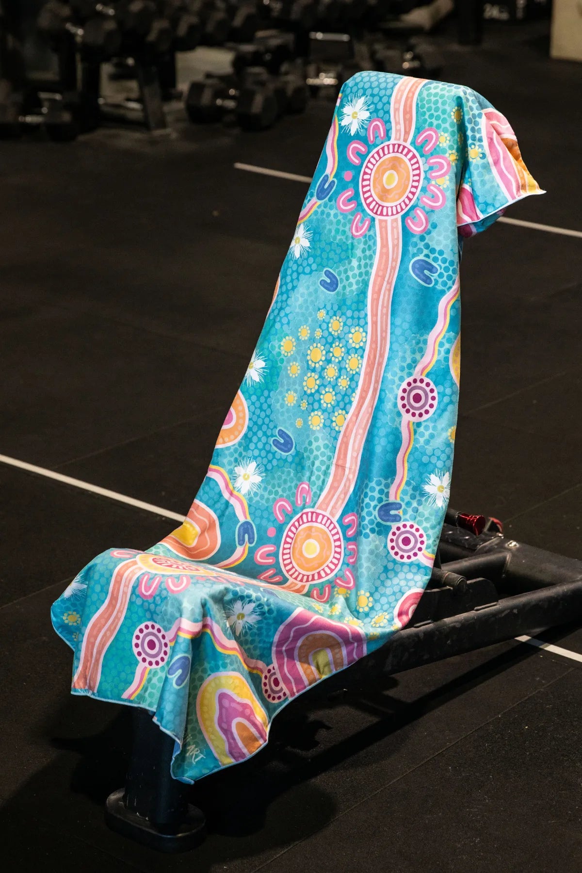 Endless Summer Indigenous hooded gym towel by Aboriginal artist Mirii Art featuring vibrant colours, 140x60cm with zip pocket in hood, stays on gym bench, quick-dry and odour resistant by Cheeky Winx Australia.