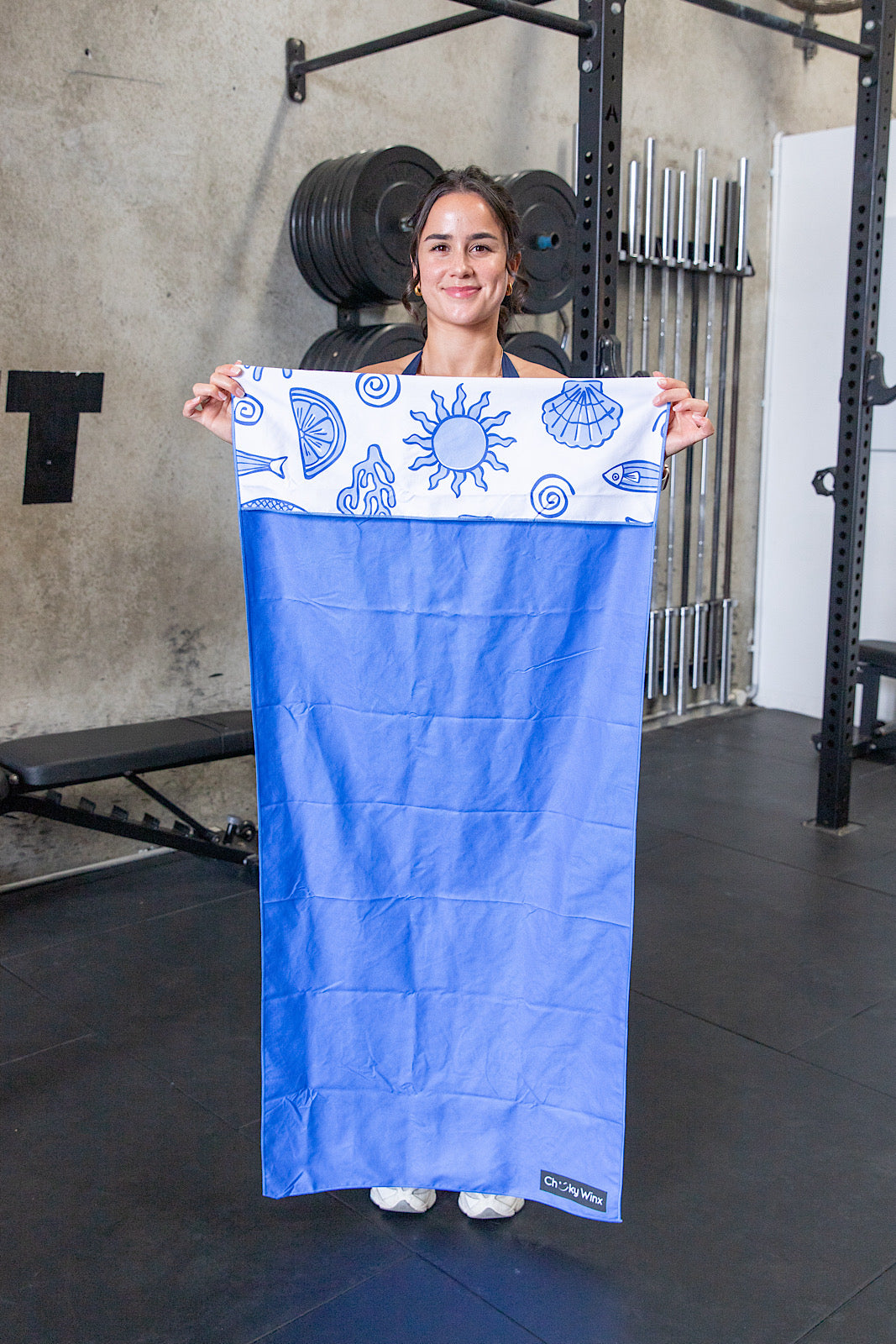 Person holding a blue towel with a pattern in a gym setting