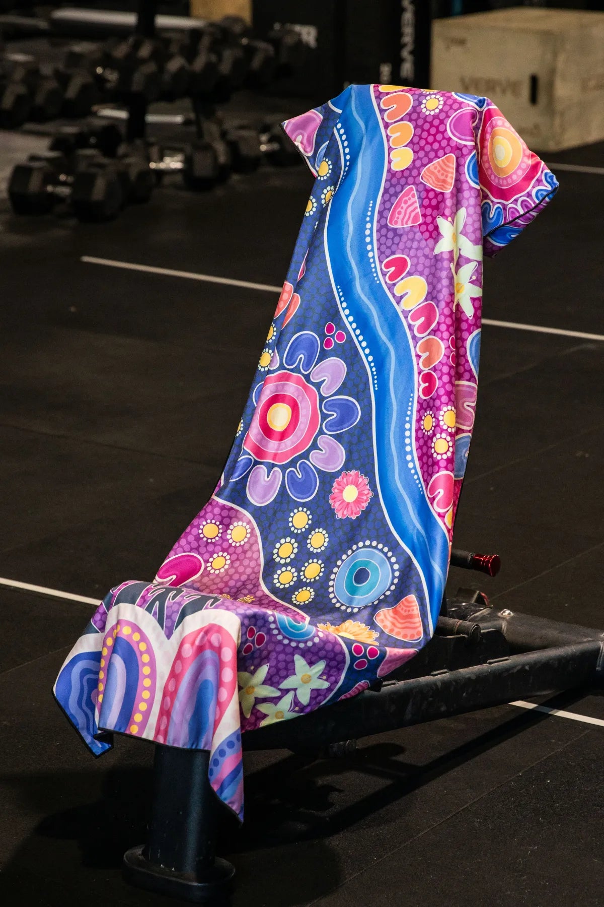 Thriving Together Indigenous hooded gym towel by Aboriginal artist Mirii Art featuring vibrant colours, 140x60cm with zip pocket in hood, stays on gym bench, quick-dry and odour resistant by Cheeky Winx Australia.