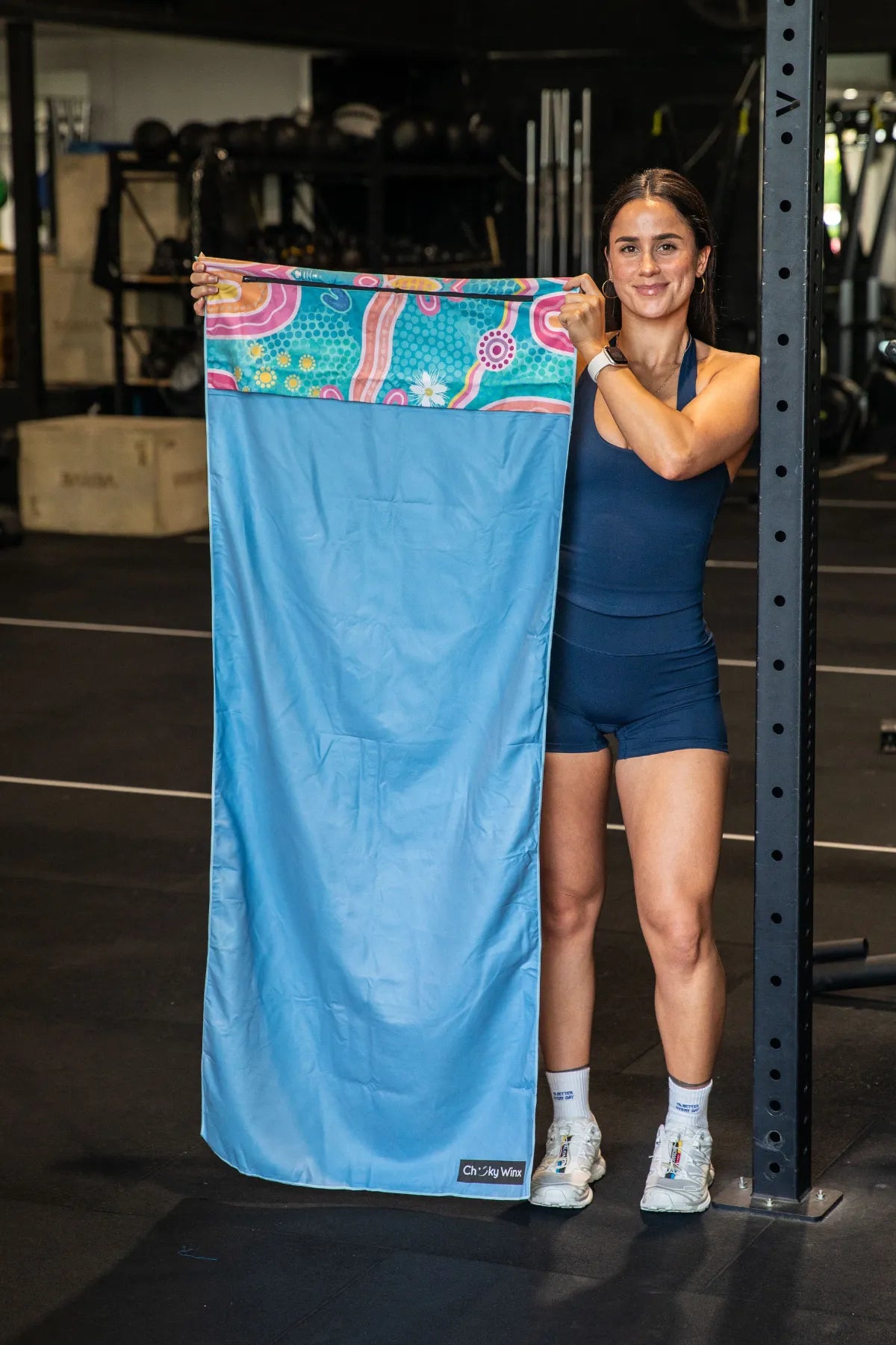 Endless Summer Indigenous hooded gym towel by Aboriginal artist Mirii Art featuring vibrant colours, 140x60cm with zip pocket in hood, stays on gym bench, quick-dry and odour resistant by Cheeky Winx Australia.