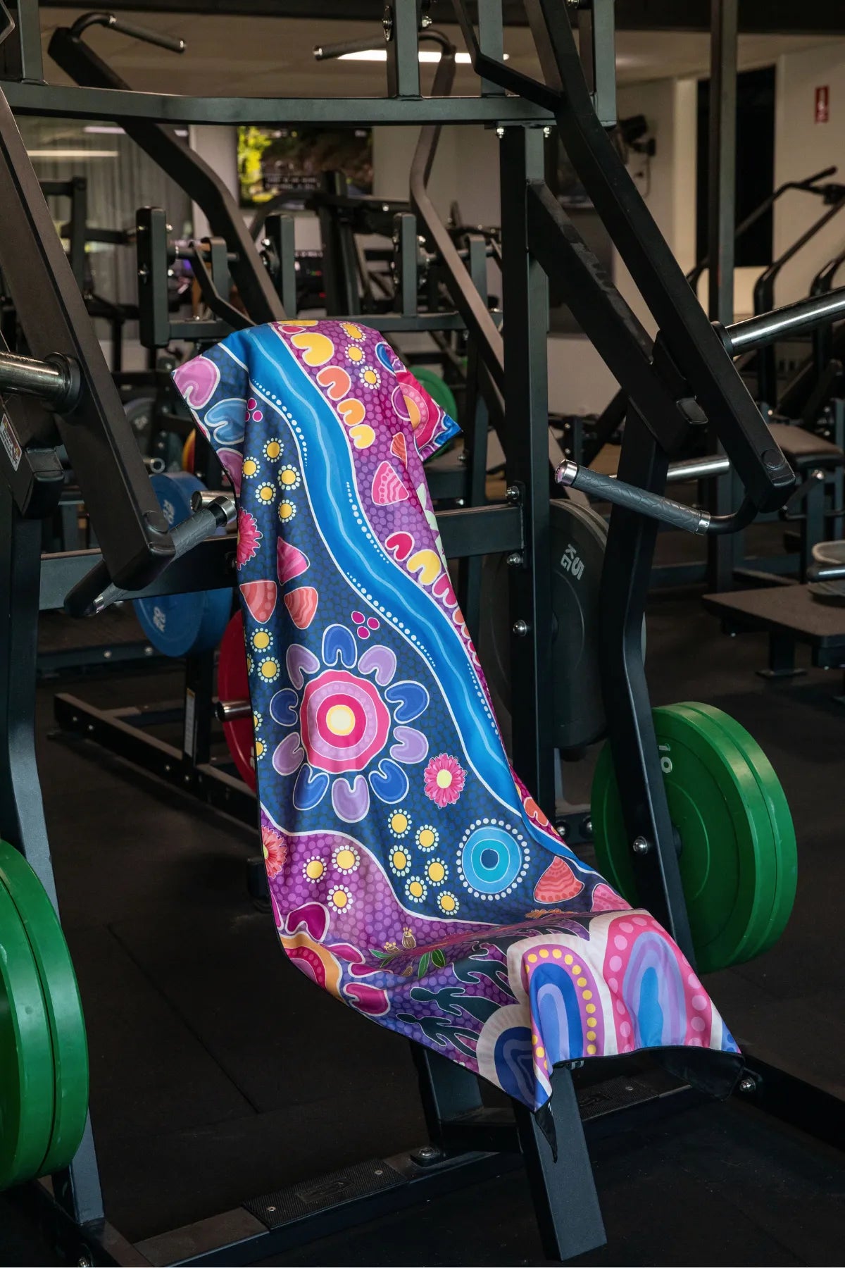 Thriving Together Indigenous hooded gym towel by Aboriginal artist Mirii Art featuring vibrant colours, 140x60cm with zip pocket in hood, stays on gym bench, quick-dry and odour resistant by Cheeky Winx Australia.